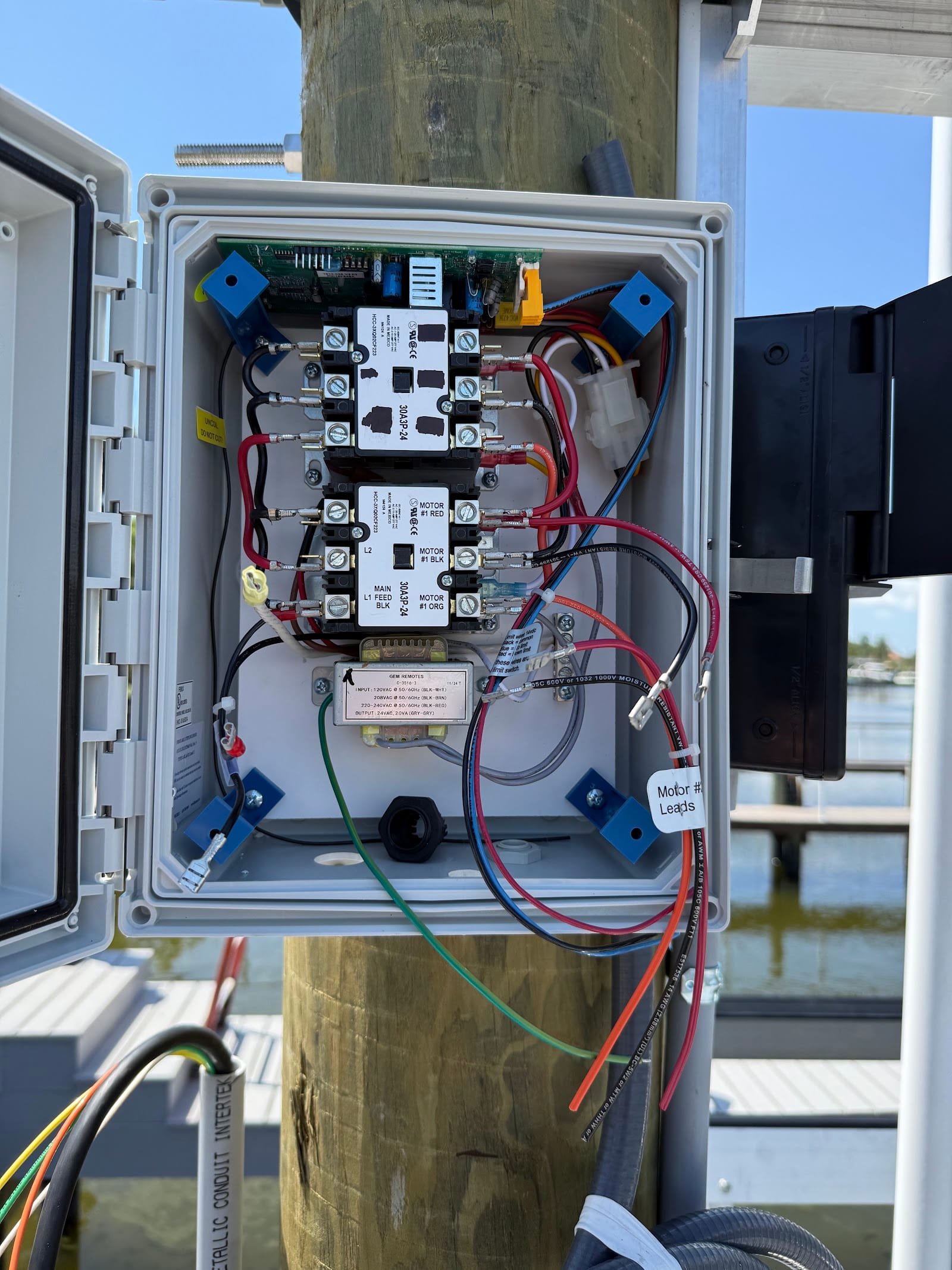 Boat lift motor control box with contactors and GEM remote receiver wired on a dock piling by Lightning Bay Electric on a Tampa Bay canal