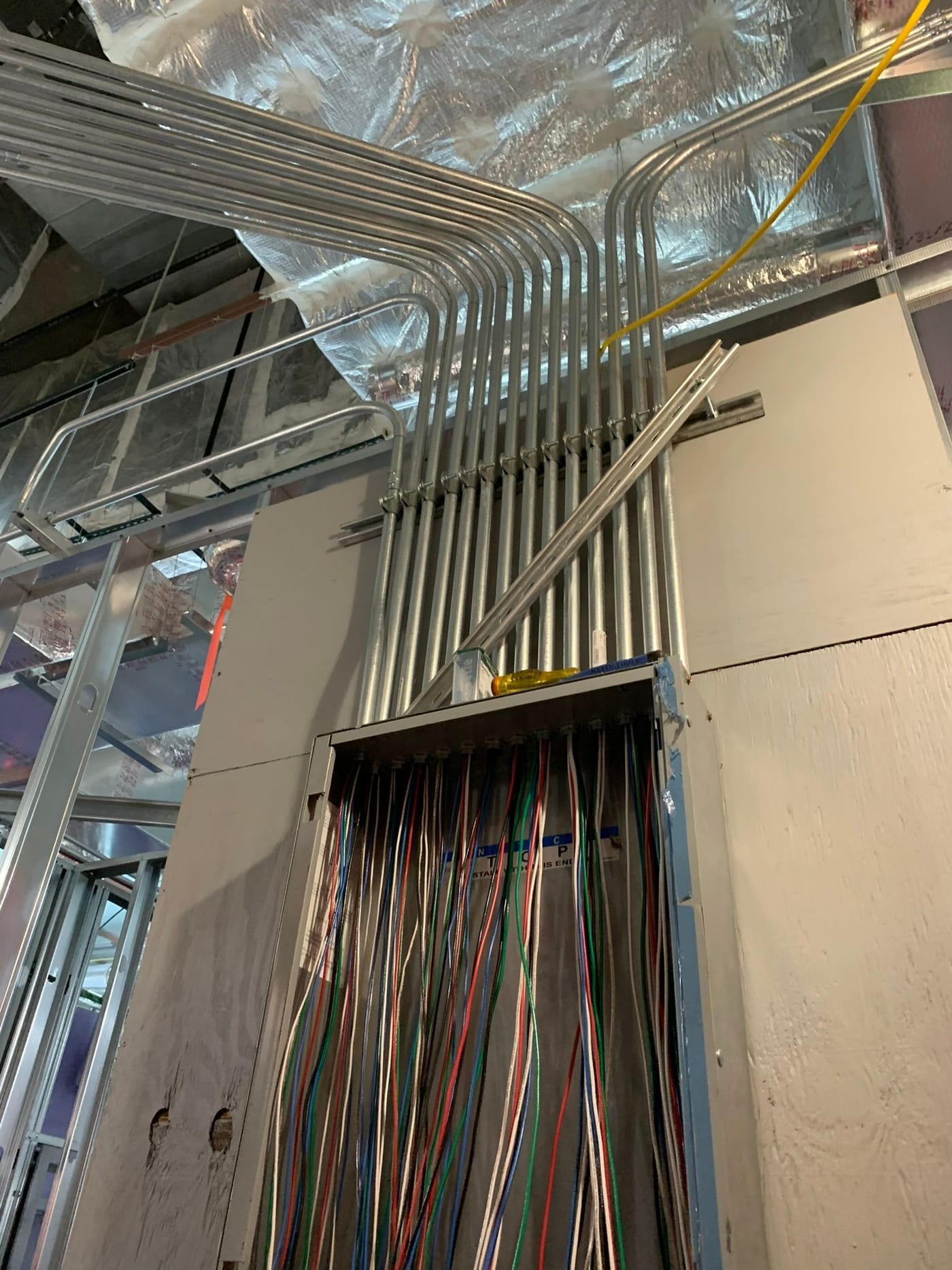Bank of EMT conduits bent and run overhead into a commercial electrical panel by Lightning Bay Electric on a Tampa, FL build-out