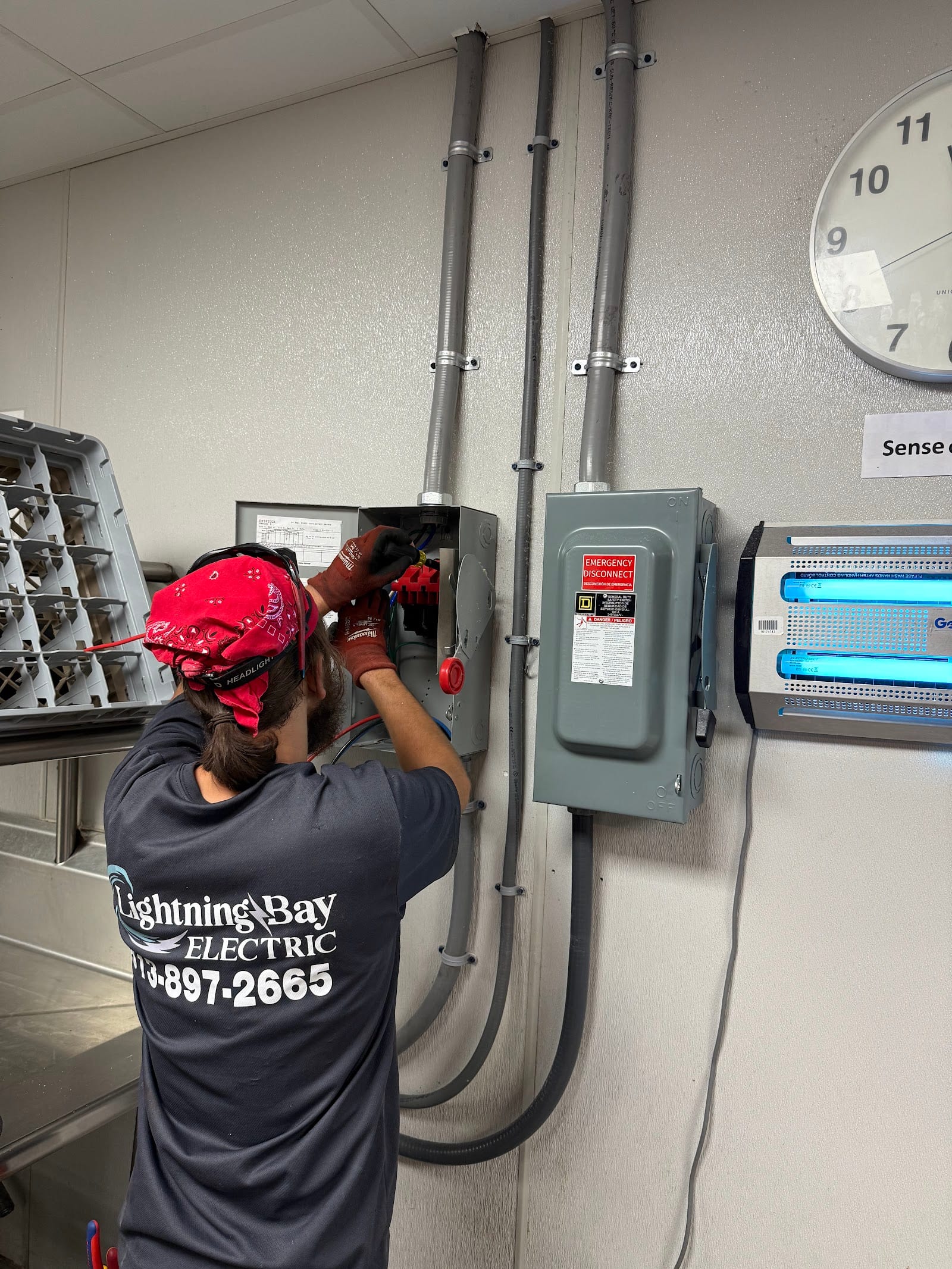 Lightning Bay Electric electrician in company shirt wiring a Square D emergency disconnect in a Tampa, FL commercial kitchen