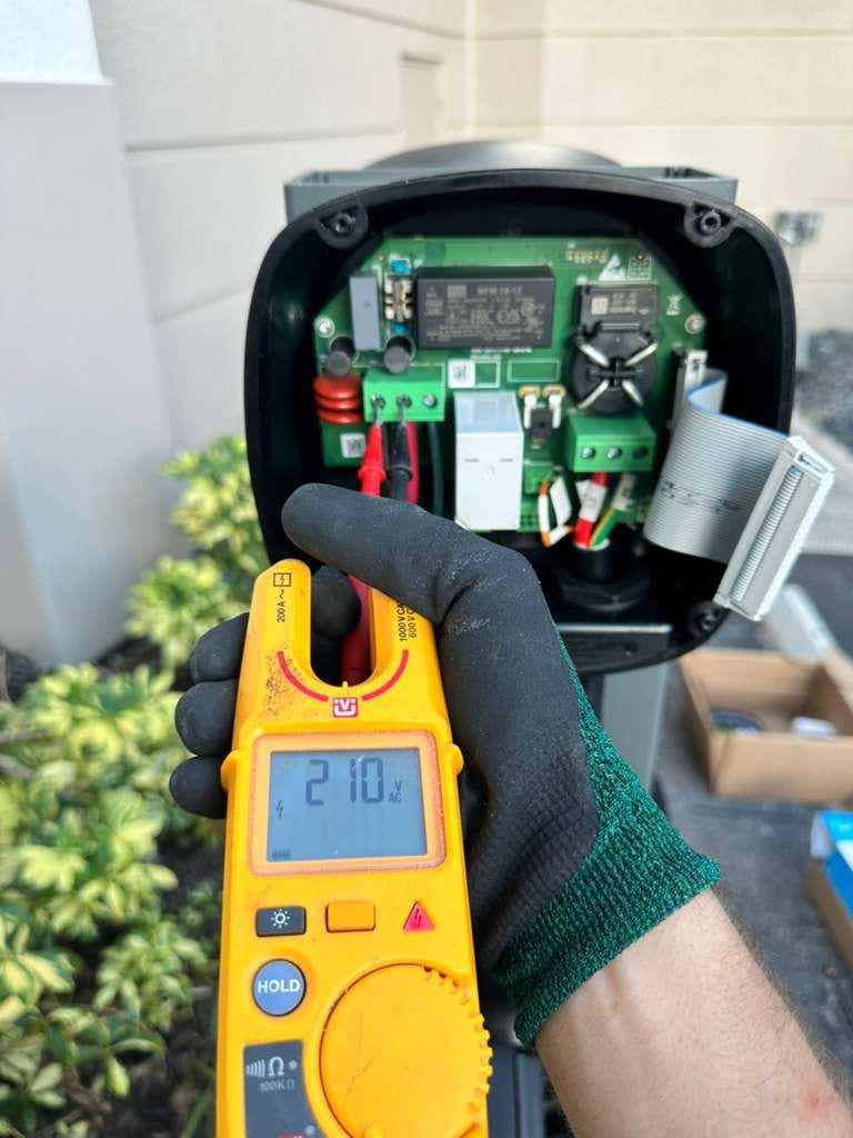 Lightning Bay Electric technician verifying 210 volts with a Fluke tester inside an EV charger during diagnostics at a Tampa Bay home