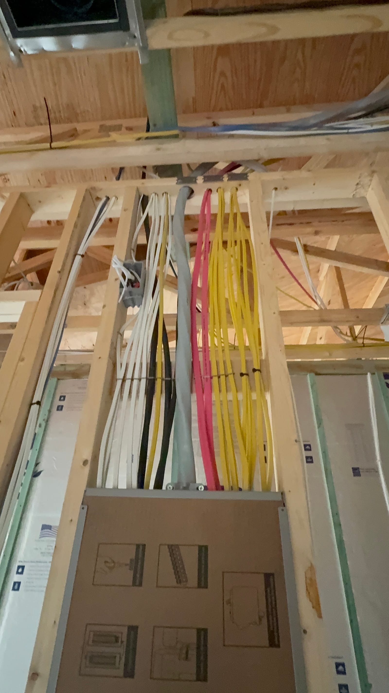 Color-coded rough-in wiring bundled through new framing down to the electrical panel by Lightning Bay Electric on a new-construction home in the Tampa Bay area