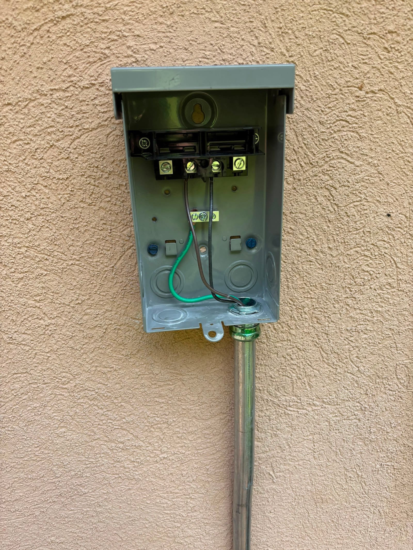 New outdoor pull-out AC disconnect box and EMT conduit installed on a stucco wall by Lightning Bay Electric in Tampa, FL
