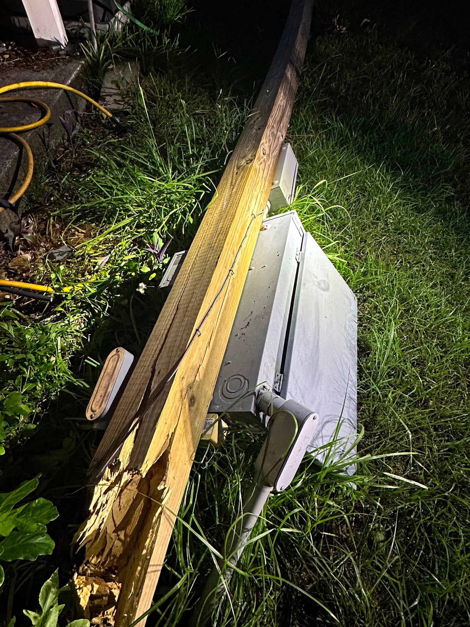 Storm-snapped electrical service pole with meter cans on the ground at night, an emergency service repair handled by Lightning Bay Electric in Tampa Bay