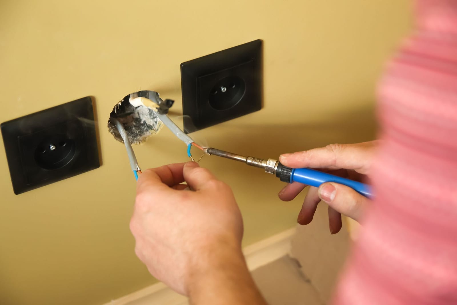 Electrician repairing the wiring behind a wall outlet, the kind of outlet and switch repair Lightning Bay Electric handles daily across Tampa, FL