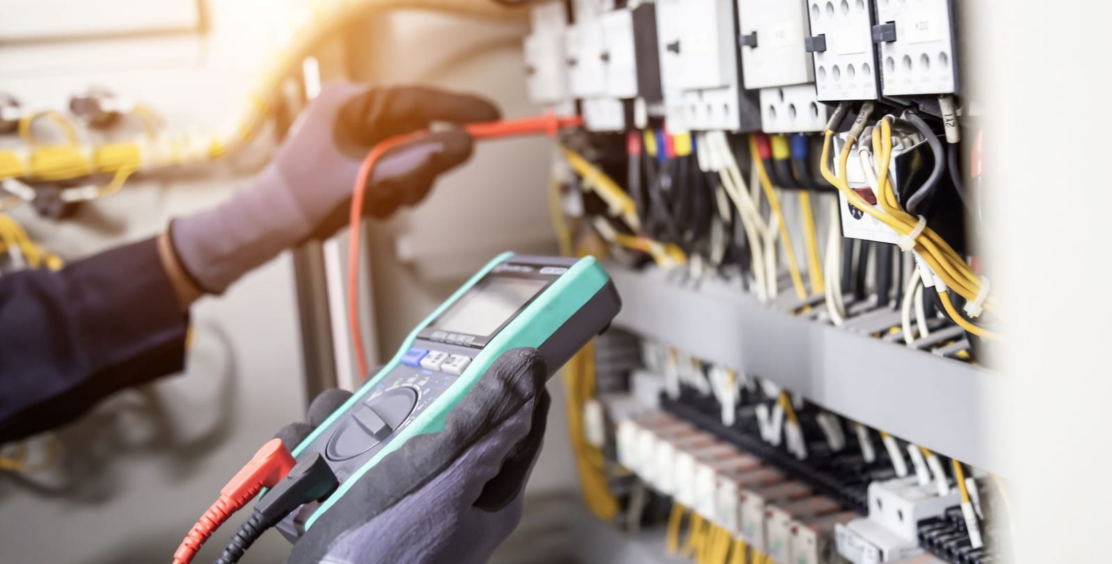 Electrician testing contactors in a control panel with a digital multimeter, electrical troubleshooting by Lightning Bay Electric in Brandon, FL